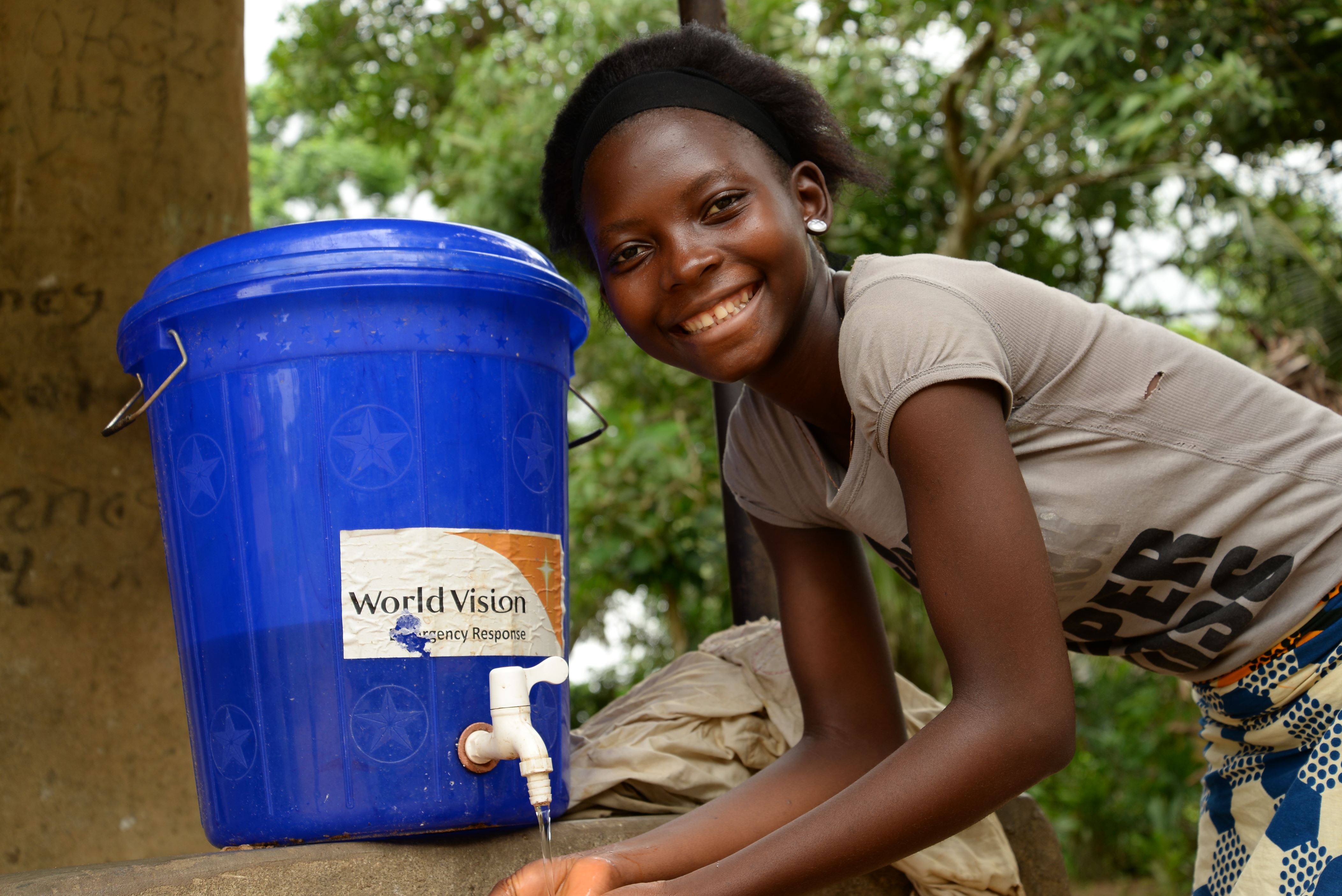 Young African girl, getting water from a World Vision branded tap