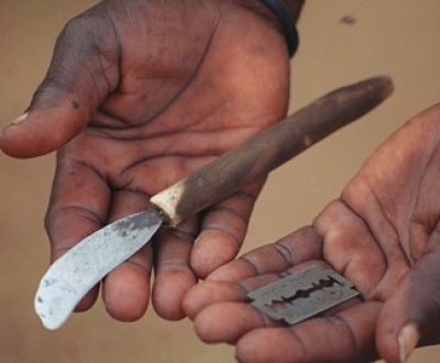 A close-up of a African child's hands holding a blade.