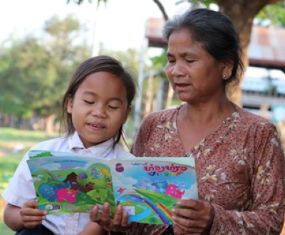 Girl from Laos reading a children's story book with her grandmother