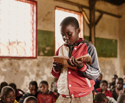 Boy from Malawi reading a book in his class