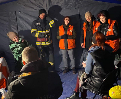 A group of Ukrainian refugees sitting in a circle at a refugee camp in Romania, talking to World Vision volunteers