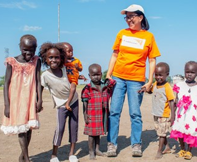World Vision staff member holding hands of children in South Sudan