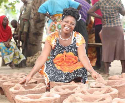 A women siting near some mud pots.