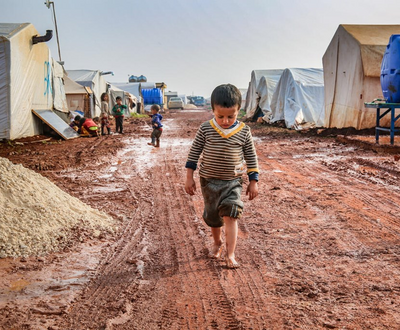 A boy walking the mud in an internally displaced camp in northwest Syria.