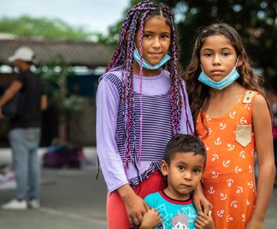 Reymar, 12, and her brother, Luismeiquer, 3, and sister Rassel, 10, stand together at an outdoor community soccer court in Huaquillas, Ecuador.