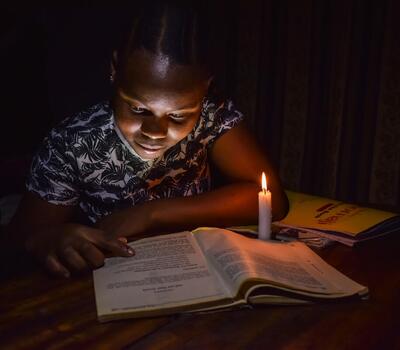 A child studying in the candle light.