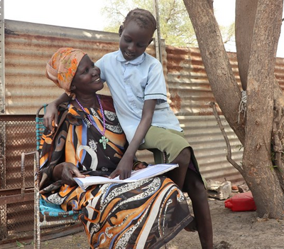 Boy sitting on his mother's lap and reading a book