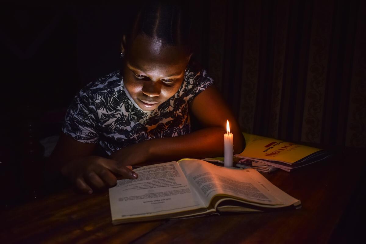 A child studying in the candle light.