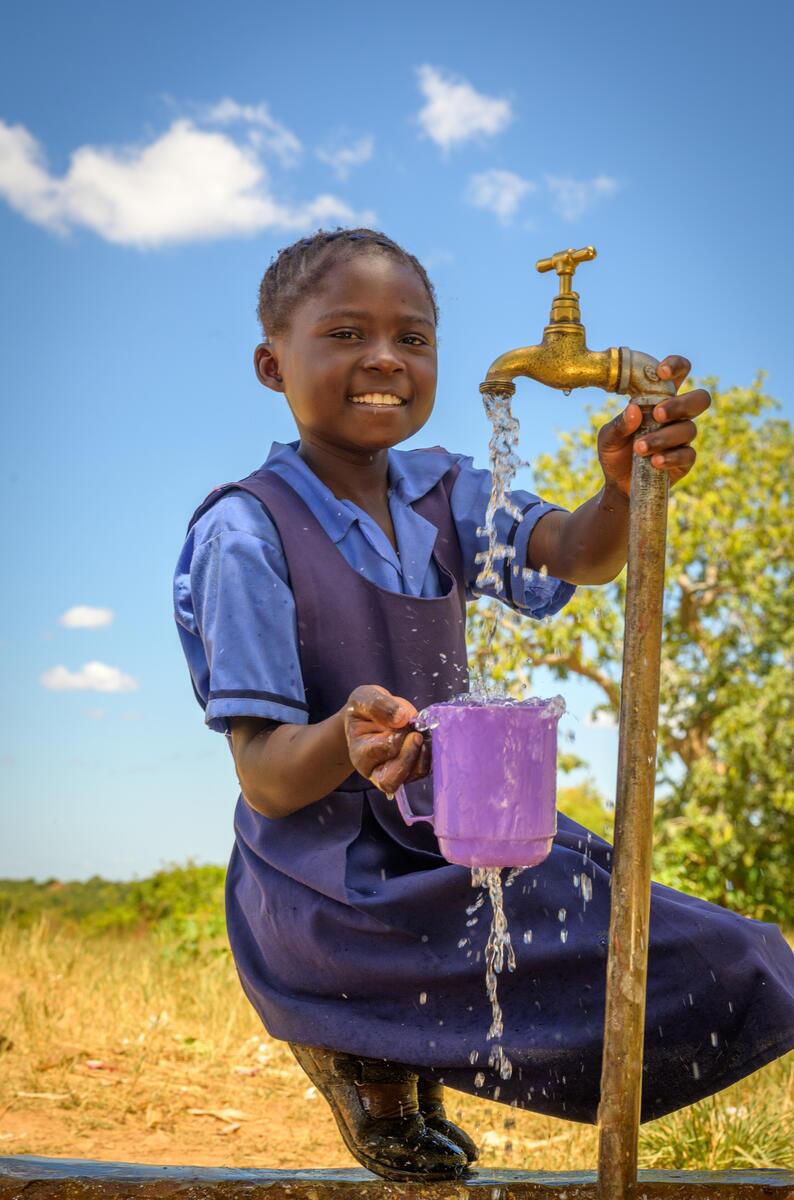 A girl child taking water in pipe.