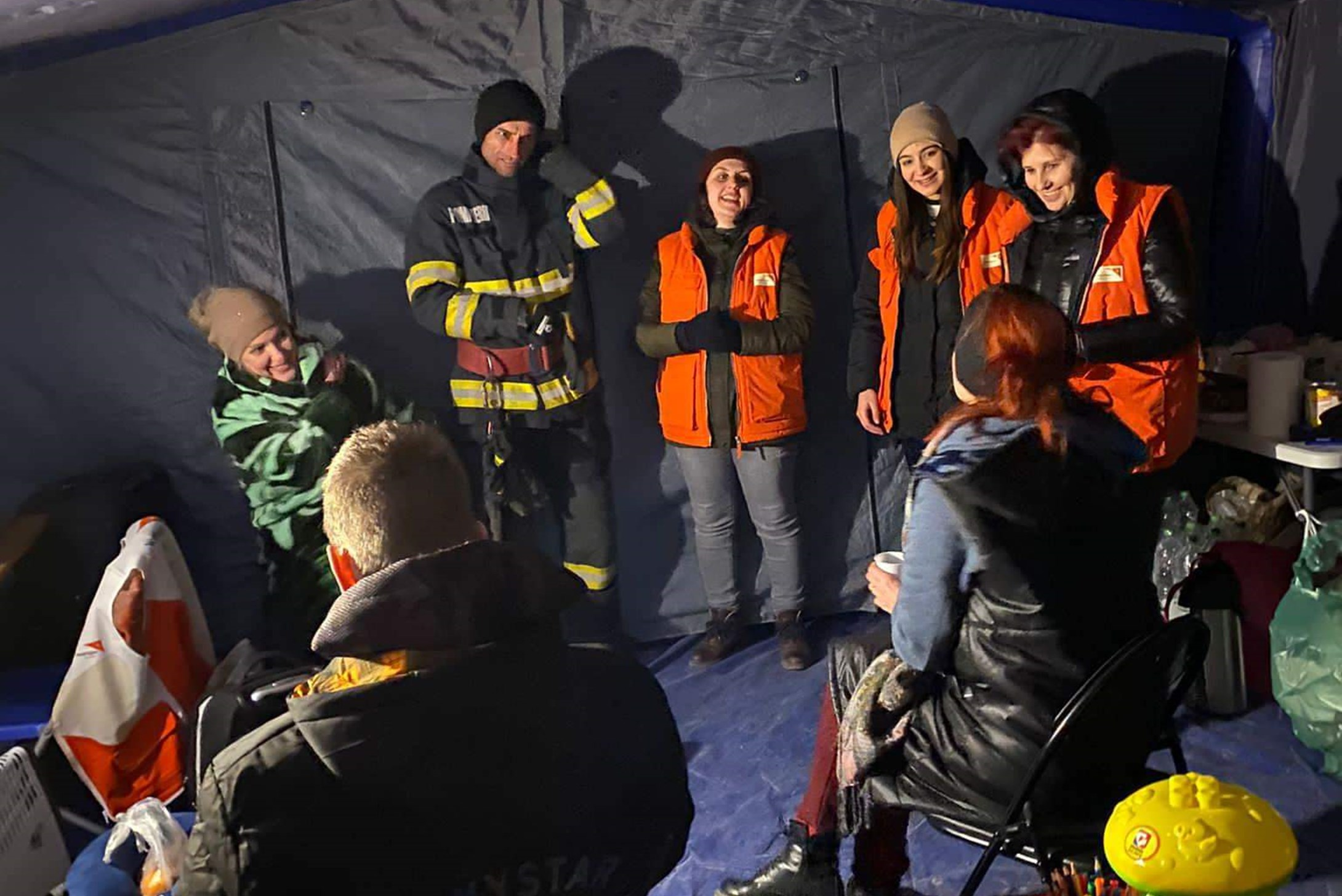 A group of Ukrainian refugees sitting in a circle at a refugee camp in Romania, talking to World Vision volunteers