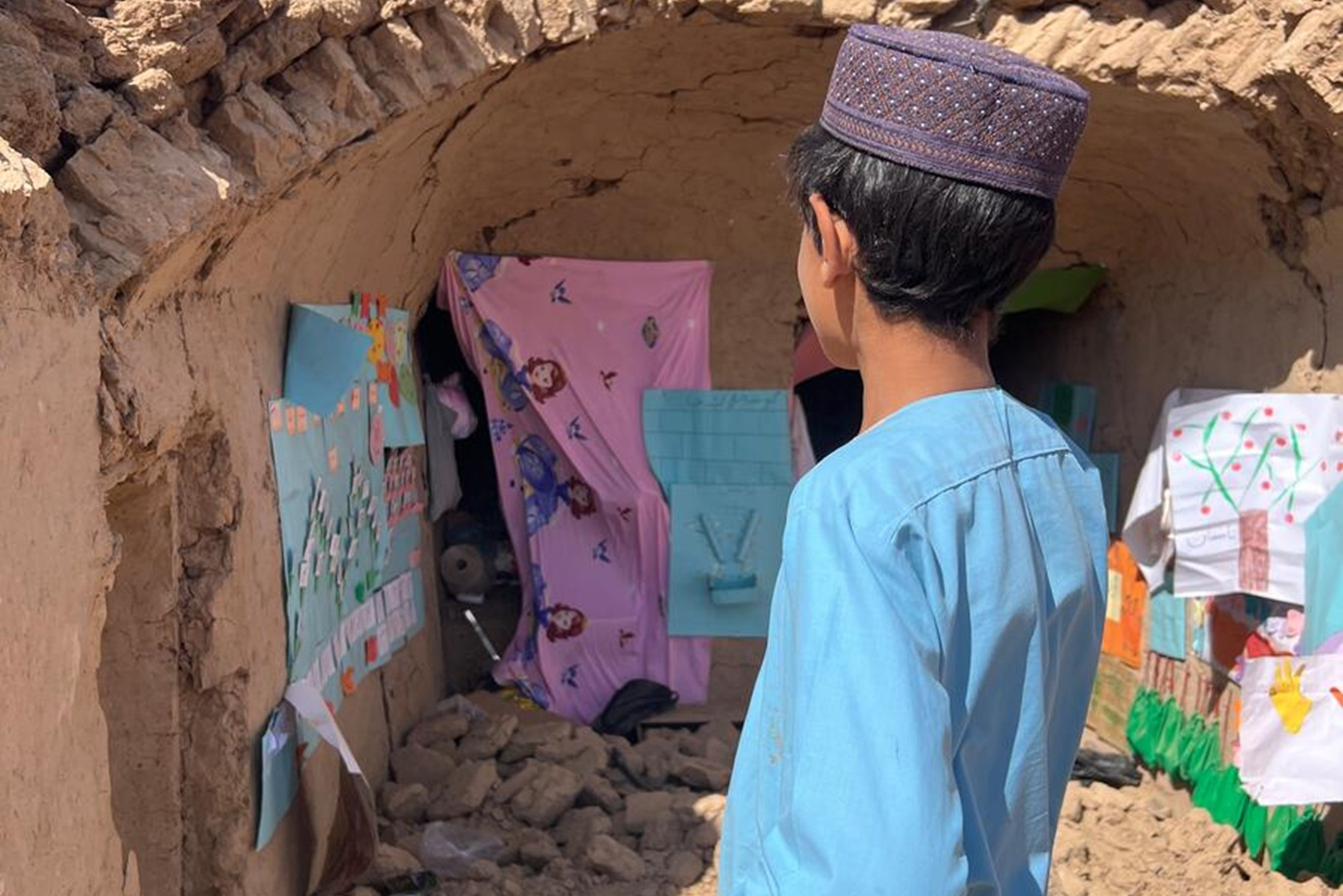 The remains of an early childhood education centre. Some of the children's paintings and visual learning charts remain, but the classroom is destroyed.