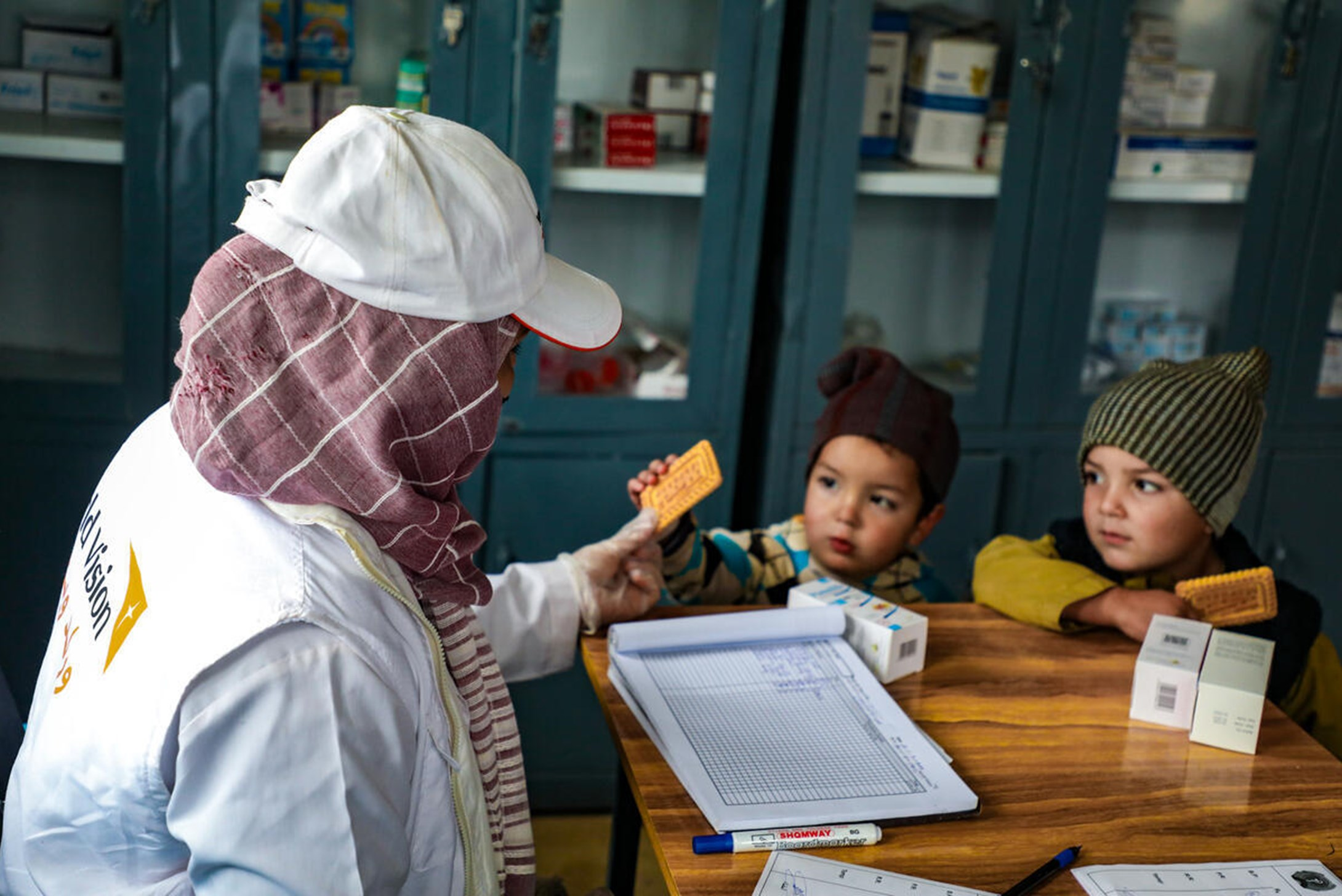 Worl vision staff giving biscuit to kids