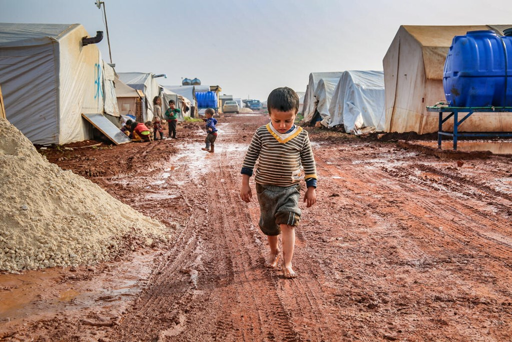 A boy walking the mud in an internally displaced camp in northwest Syria.