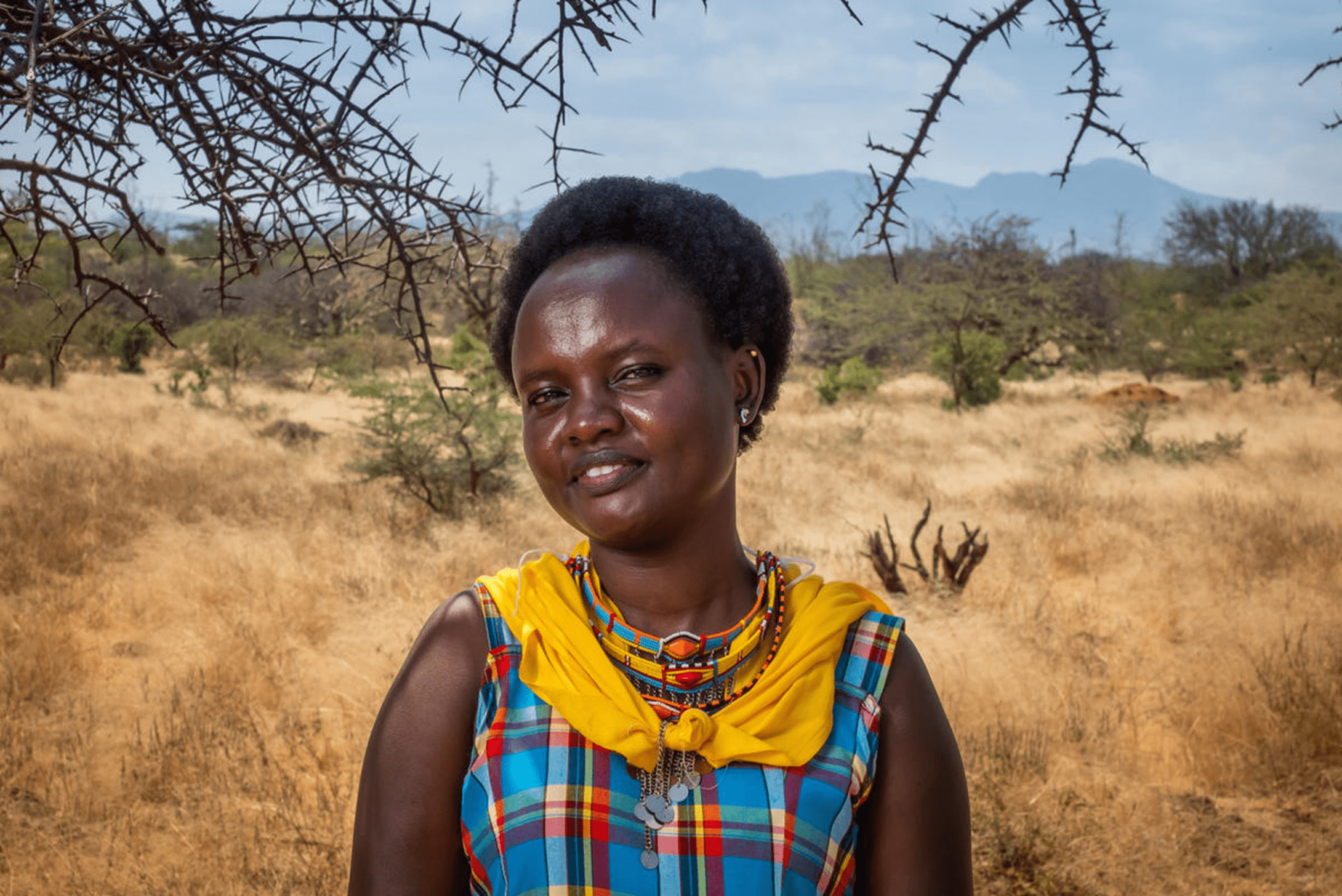 Girl from Kenya smiles at camera in field