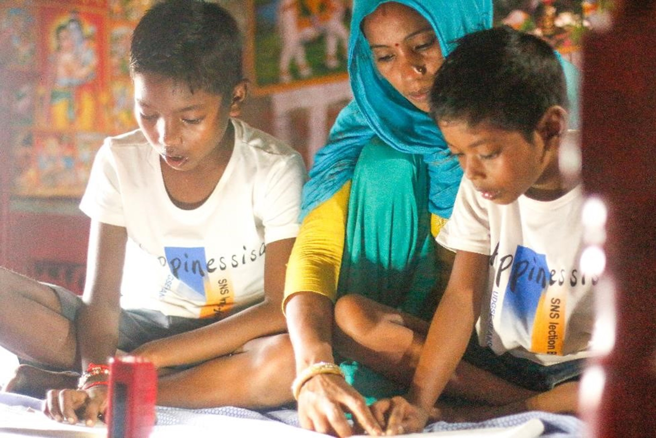 Woman from Nepal teaching two boys to read