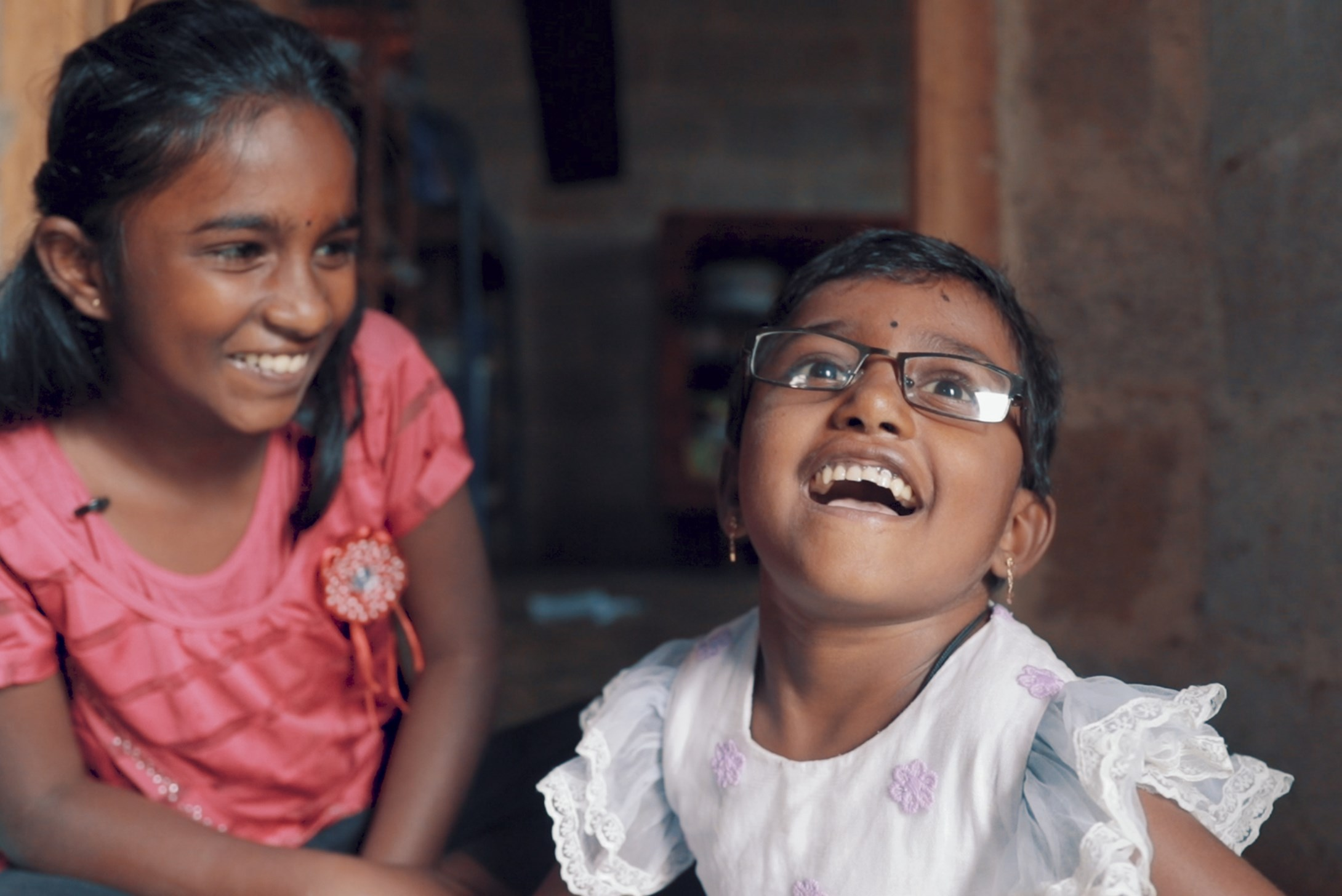 Two girls from Sri Lanka sitting on the floor and laughing