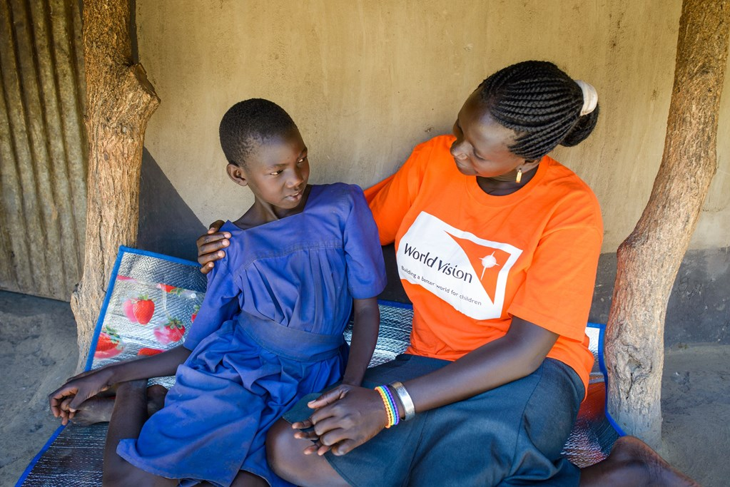 Six World Vision staff in orange tshirts in front of a stand volunteering at a World Vision event